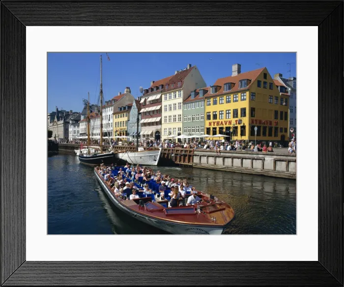 Framed Print : Tourists on boat trip pass painted buildings on the busy waterfront of Nyhavn Framed Print : Tourists on boat trip pass painted buildings on the busy waterfront of Nyhavn