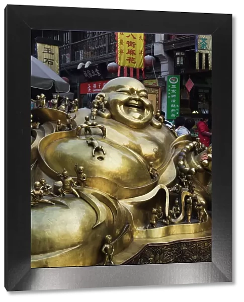 A golden statue of a reclining laughing Buddha covered in small Buddhas