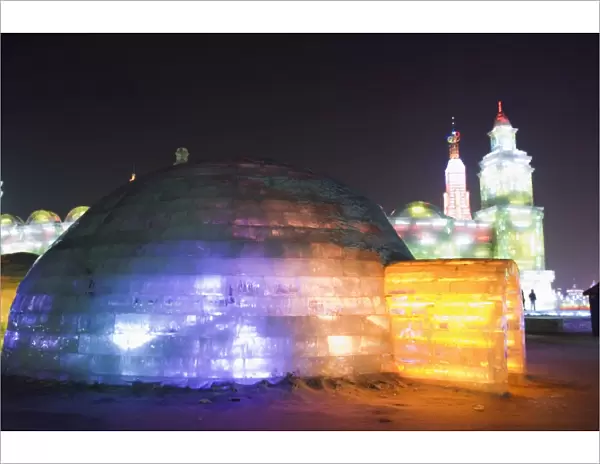 An igloo ice sculpture illuminated at night at the Ice Lantern Festival