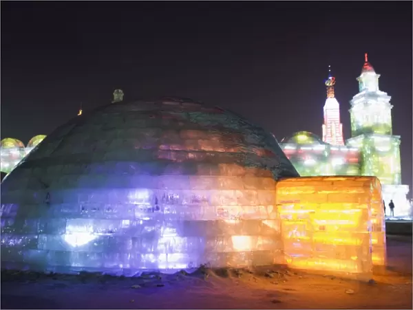 An igloo ice sculpture illuminated at night at the Ice Lantern Festival