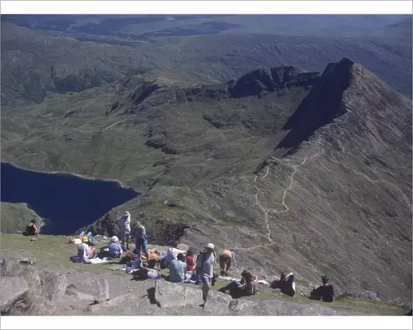 Walkers relaxing at the summit of Mount Snowdon, with Llyn Llydaw reservoir