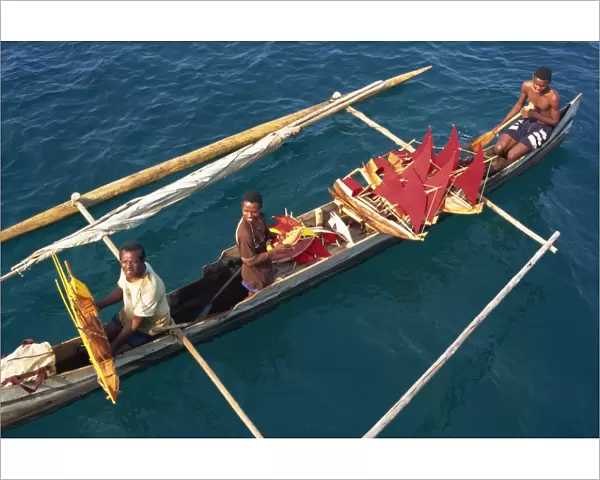 Men in outrigger canoes selling model boats with red sails, Nosy Be, Madagascar, Africa