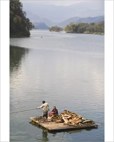 Couple on wooden raft with firewood, Fewa (Phewa) Lake, Pokhara, Nepal, Asia