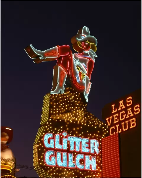 Close-up of neon sign of a cowgirl advertising Glitter Gulch at night in Las Vegas