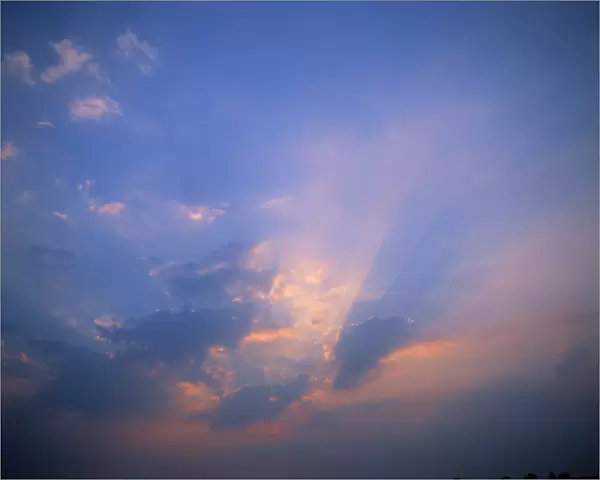Rays of light bursting through clouds in a blue sky