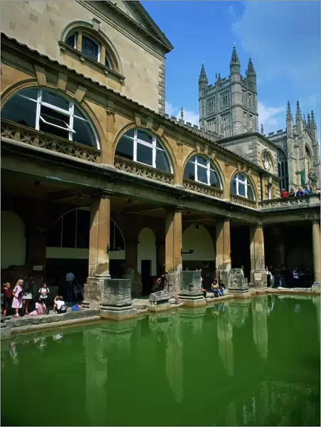 Visitors in the Roman Baths, with the Abbey beyond in Bath, UNESCO World Heritage Site