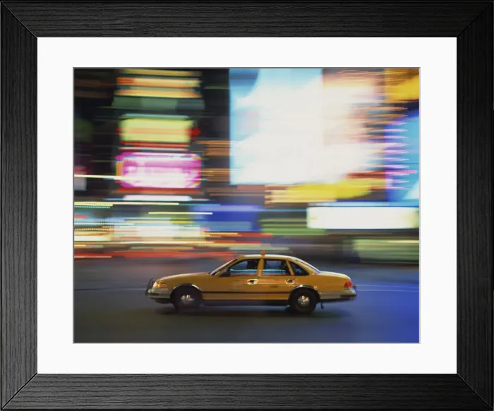 Framed Print : Yellow cab driving past blurred neon lights at night in Times Square in New York Framed Print : Yellow cab driving past blurred neon lights at night in Times Square in New York