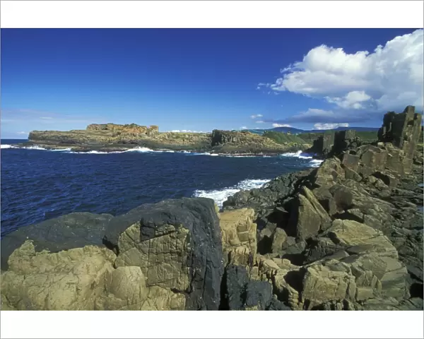 Columnar structures, created during cooling of basalt lava, with an intrusion or dyke of darker rock in the foreground, near Bombo Beach, Kiama, south coast, New South Wales