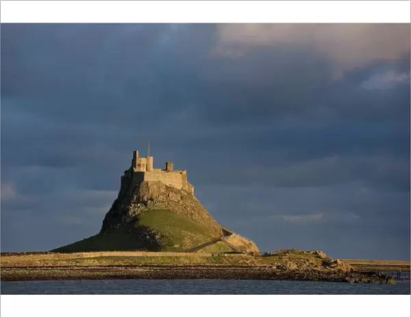 Lindisfarne Castle bathed in afternoon sunlight against a stormy sky, Holy Island
