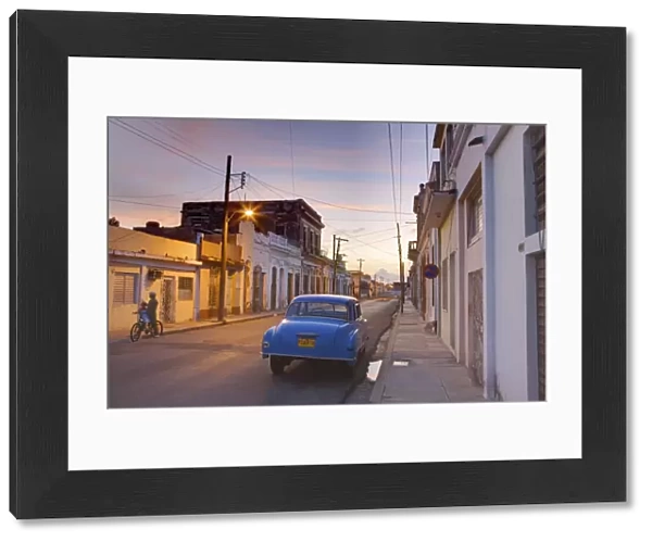Street scene at twilight with classic blue American car, Cienfuegos, Cuba