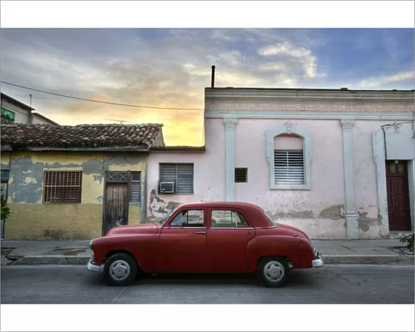 Classic red American car parked outside houses at sunset, Cienfuegos, Cuba