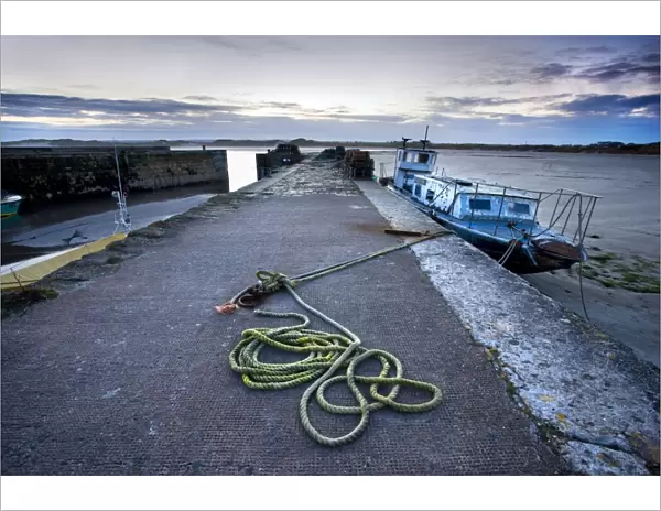 Beadnell Harbour at dusk showing old rope coiled on harbourside and dilapidated fishing boat