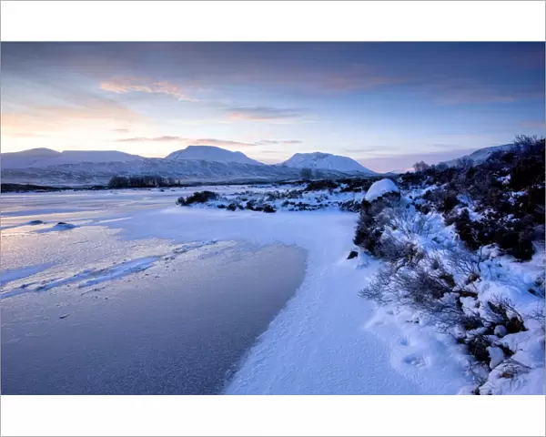 Dawn view of frozen Loch Ba on snow-covered Rannoch Moor, Highland, Scotland
