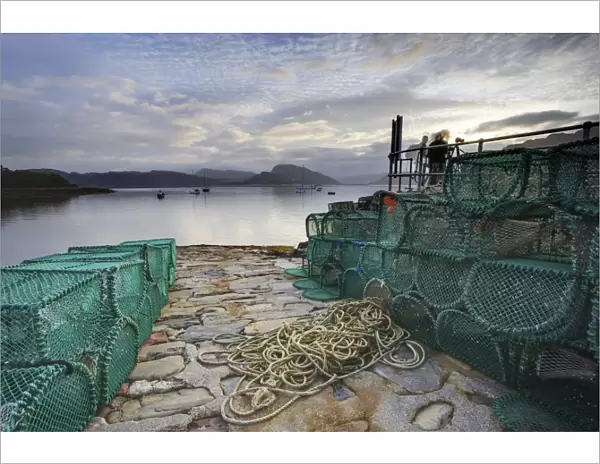 View out to sea from stone slipway at dawn, with lobster pots and ropes in foreground