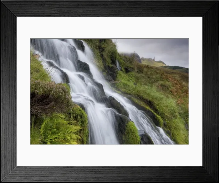 Framed Print : Waterfall cascading down grassy slope with Old Man of Storr in background Framed Print : Waterfall cascading down grassy slope with Old Man of Storr in background