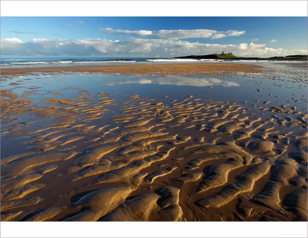 View across Embleton Bay at low tide towards the ruins of Dunstanburgh Castle