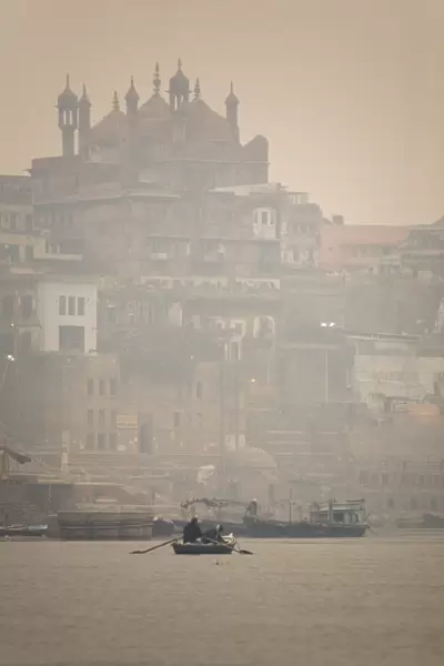 A boat is rowed on a typically foggy morning in the Ganga (Ganges) River at Varanasi