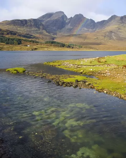View across the clear waters of Loch Slapin to rainbow over the Cuillin Hills