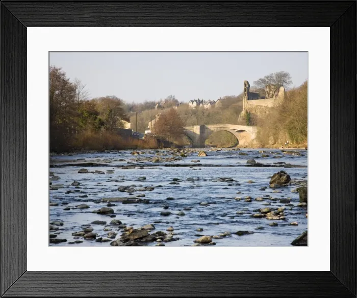 Framed Print : View along the boulder-strewn River Tees to the ruined castle and 16th century County Bridge