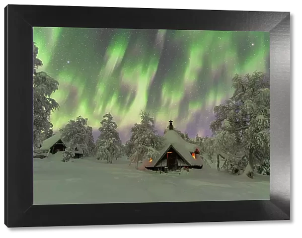 Winter view of a typical wooden hut lit by the fire in the frozen wood during a Northern Lights (Aurora Borealis) storm, Finnish Lapland, Finland, Europe