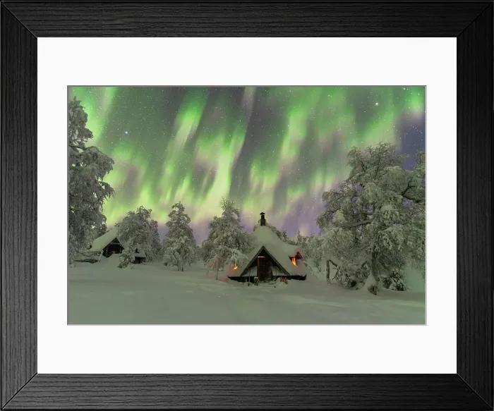 Framed Print : Winter view of a typical wooden hut lit by the fire in the frozen wood during a Northern Lights (Aurora Borealis) storm, Finnish Lapland, Finland, Europe