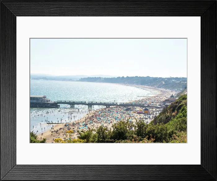 Framed Print : Sunny beach day with crowded sandy shore and pier, clear blue water, and lush greenery in the foreground in Bournemouth, Dorset, England, United Kingdom, Europe Framed Print : Sunny beach day with crowded sandy shore and pier, clear blue water, and lush greenery in the foreground in Bournemouth, Dorset, England, United Kingdom, Europe