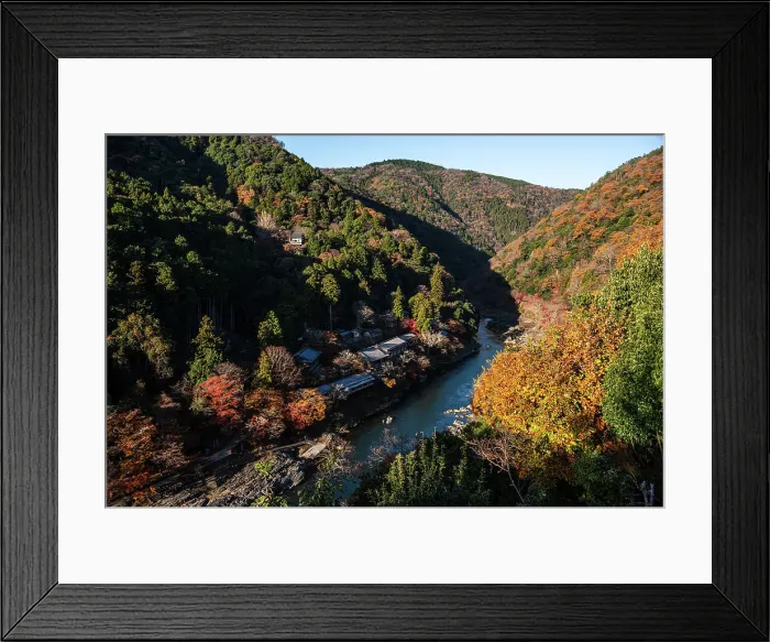 Framed Print : Autumnal forests with deep blue Katsura Riverwith temple roofs on the river bank in Arashiyama of Kyoto, Honshu, Japan, Asia