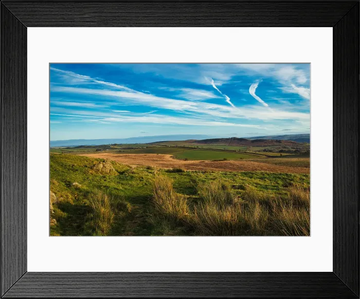 Framed Print : Scenic landscape with lush green fields, rolling hills, and a clear blue sky with wispy clouds at Sycamore Gap, Northumberland, UK