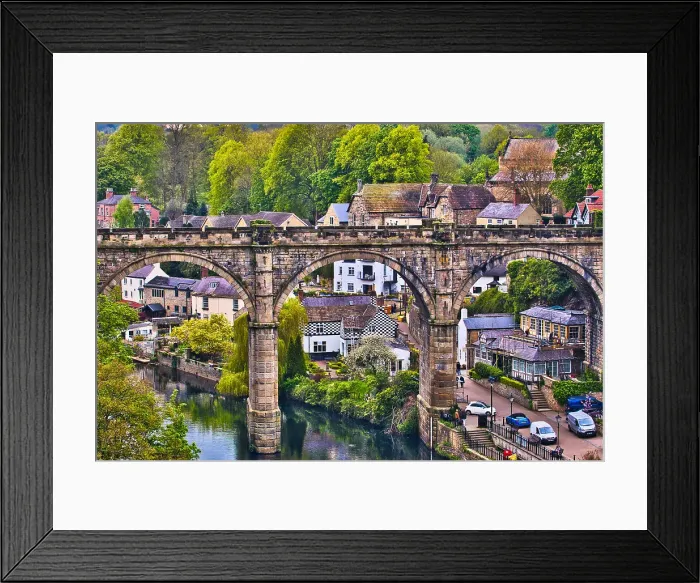 Framed Print : A picturesque view of a stone bridge arching over a river in a quaint village, surrounded by lush greenery and historic buildings Framed Print : A picturesque view of a stone bridge arching over a river in a quaint village, surrounded by lush greenery and historic buildings