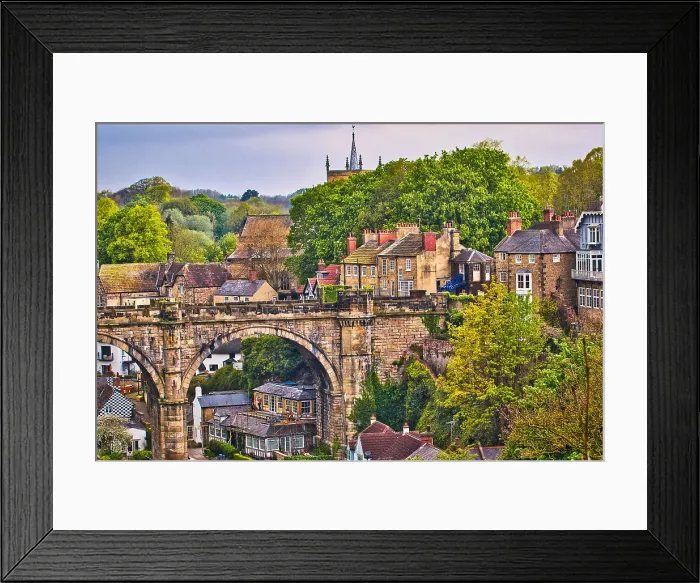 Framed Print : Scenic view of a historic town with a prominent stone bridge and lush greenery. Traditional architecture and a church spire add to the charm Framed Print : Scenic view of a historic town with a prominent stone bridge and lush greenery. Traditional architecture and a church spire add to the charm