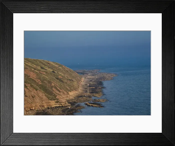 Framed Print : Coastal landscape with a serene blue ocean beside a rugged cliff under a clear sky in Filey, England Framed Print : Coastal landscape with a serene blue ocean beside a rugged cliff under a clear sky in Filey, England