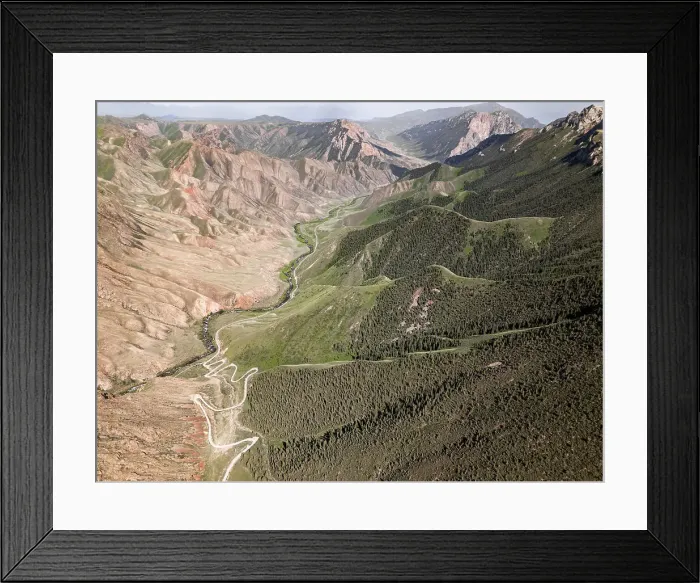 Framed Print : Aerial view of a winding mountain road curves, Kalmak Ashuu Pass, through lush greenery in Kyrgyzstan, Central Asia, Asia Framed Print : Aerial view of a winding mountain road curves, Kalmak Ashuu Pass, through lush greenery in Kyrgyzstan, Central Asia, Asia