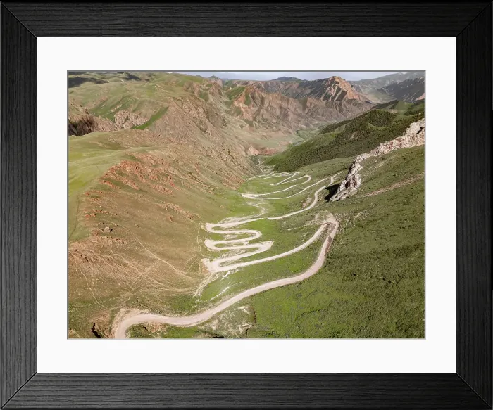 Framed Print : Aerial view of a winding mountain road curves, Kalmak Ashuu Pass, through lush greenery in Kyrgyzstan, Central Asia, Asia Framed Print : Aerial view of a winding mountain road curves, Kalmak Ashuu Pass, through lush greenery in Kyrgyzstan, Central Asia, Asia