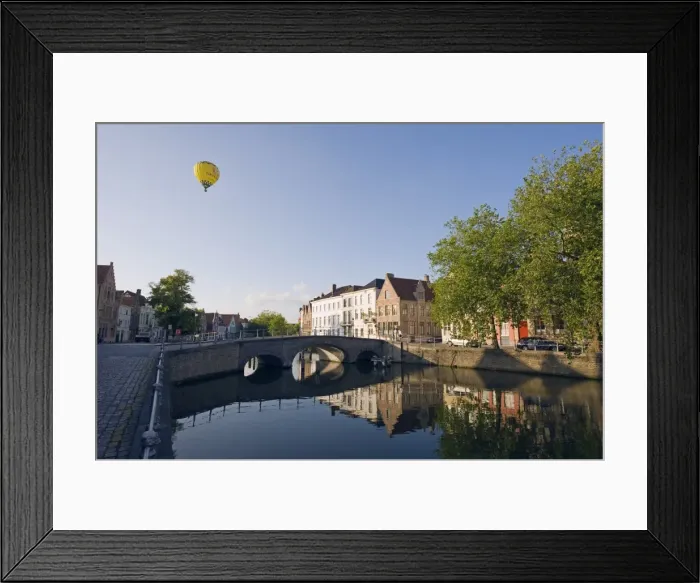 Framed Print : Hot air balloon floating over rooftops, houses reflected in a canal, old town Framed Print : Hot air balloon floating over rooftops, houses reflected in a canal, old town