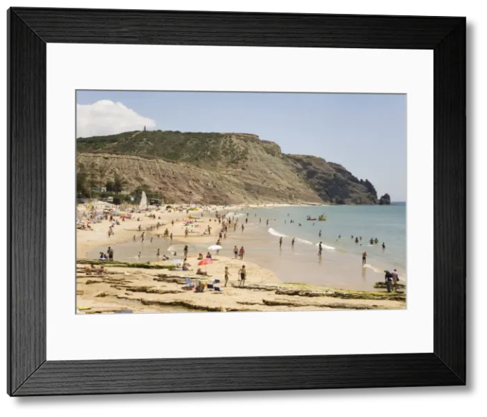 Framed Print : People enjoy sunshine and golden sand at the Praia da Luz beach in Lagos Framed Print : People enjoy sunshine and golden sand at the Praia da Luz beach in Lagos