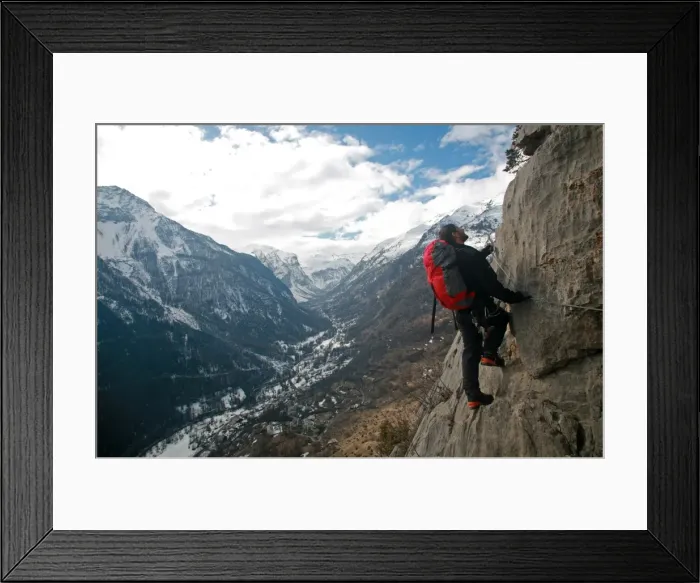 Framed Print : A man on a via ferrata route high above the tiny village of Fressinieres