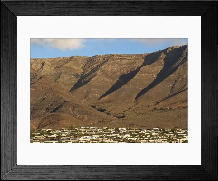 Framed Print : Towering volcanic cliffs of the Risco de Famara rising over low-rise bungalow development near Lanzarotes finest surf beach at Famara, Lanzarote, Canary Islands, Spain, Atlantic Framed Print : Towering volcanic cliffs of the Risco de Famara rising over low-rise bungalow development near Lanzarotes finest surf beach at Famara, Lanzarote, Canary Islands, Spain, Atlantic