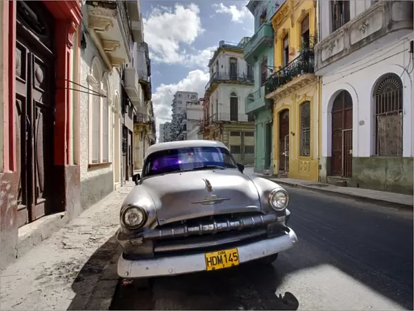 Old American Plymouth car parked on deserted street of old buildings, Havana Centro