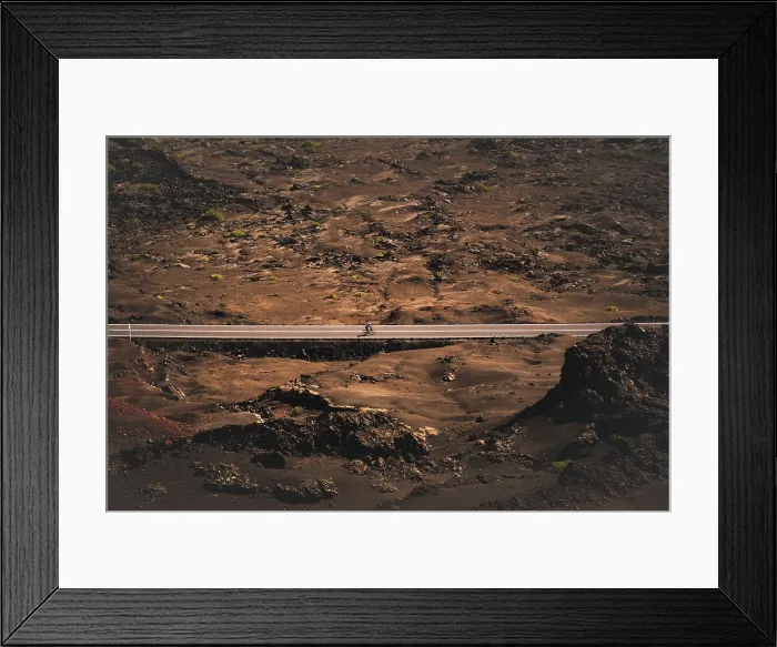 Framed Print : A cyclist cycling on a road in the Timanfaya national park in Lanzarote in the Canary Islands, Spain Framed Print : A cyclist cycling on a road in the Timanfaya national park in Lanzarote in the Canary Islands, Spain