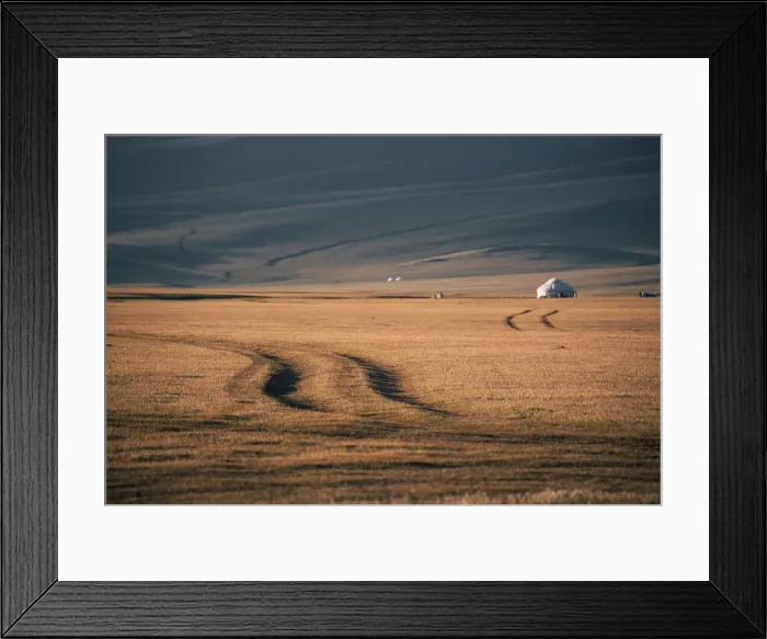Framed Print : Tire tracks weave through golden grasslands in the Song Kol region, with yurts dotting the horizon under a sunset sky