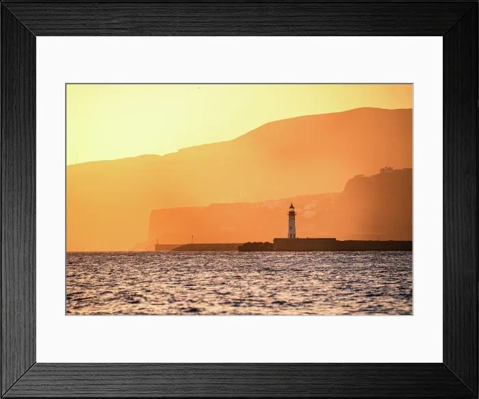 Framed Print : A lighthouse stands against golden coastal cliffs in AlmerAa, Spain, as the sunset casts a warm glow over the sea and landscape Framed Print : A lighthouse stands against golden coastal cliffs in AlmerAa, Spain, as the sunset casts a warm glow over the sea and landscape