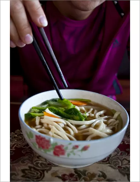 Woman eating noodle soup, Lhasa, Tibet, China, Asia