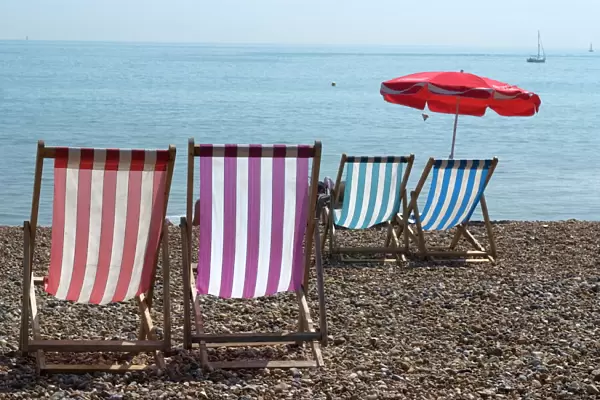 Coloured deck chairs on the pebble strand, Brighton, Sussex, England, United Kingdom