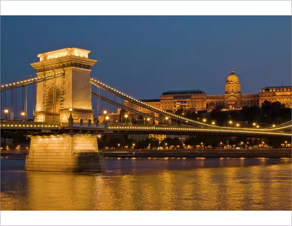 The Chain Bridge (Szechenyi Lanchid), over the River Danube, illuminated at sunset with the Hungarian National Gallery also lit, behind, Budapest