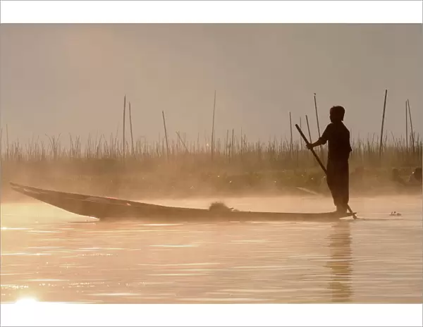Man rowing his little rowing boat at sunrise on Inle Lake, Shan States, Myanmar, Asia