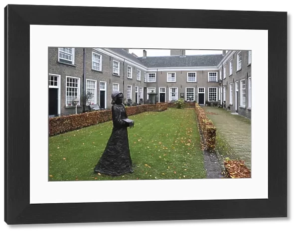 A statue of a nun stands in a courtyard of historic housing for women at the Begijnhof