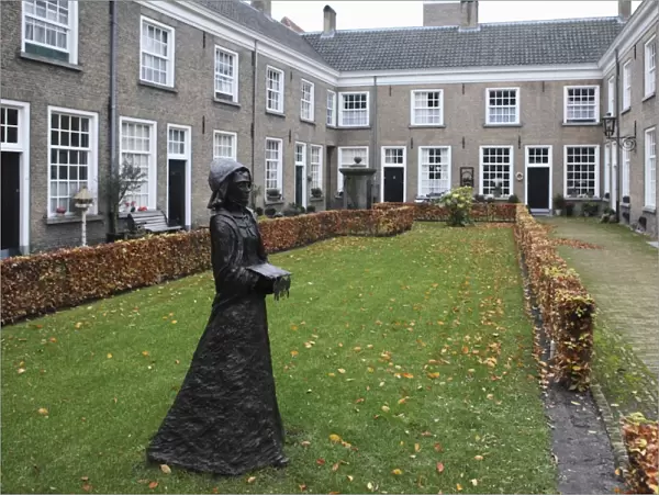A statue of a nun stands in a courtyard of historic housing for women at the Begijnhof