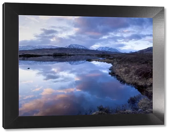 Dawn view of Loch Ba reflecting the sky and distant snow-capped mountains