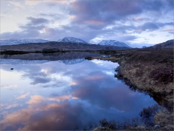 Dawn view of Loch Ba reflecting the sky and distant snow-capped mountains