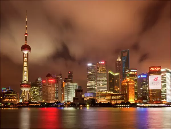 City skyline at night with Oriental Pearl Tower and Pudong skyscrapers across the Huangpu River
